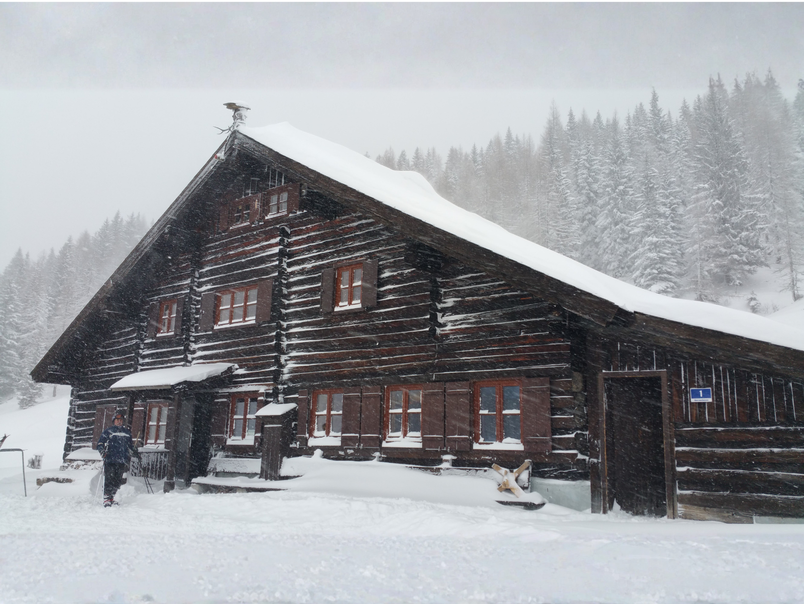 verschneite Felserhütte mit Sonne im Hintergrund