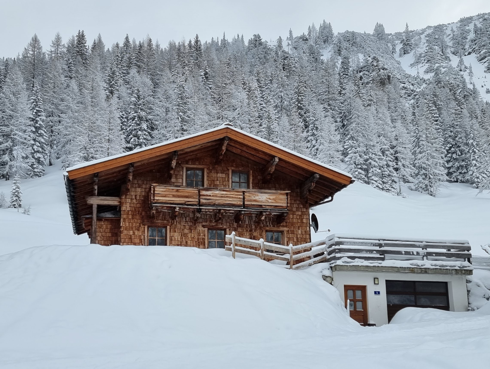 verschneite Felserhütte mit Sonne im Hintergrund 